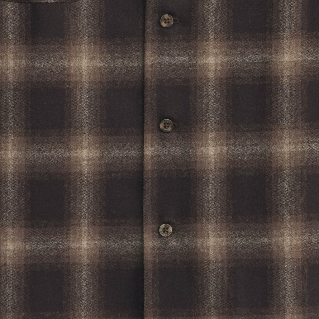 Close-up of a brown and black plaid shirt with buttons.