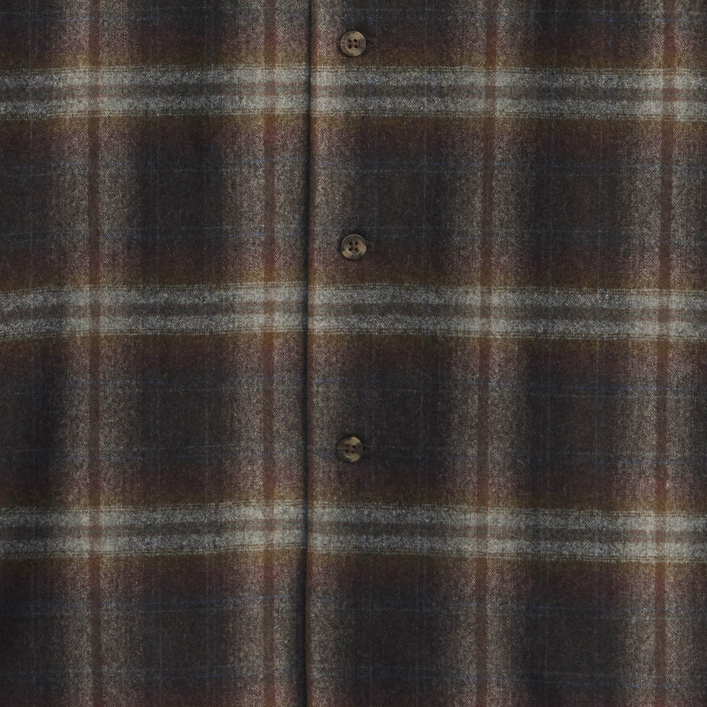 Close-up of a brown and gray plaid fabric with buttons.