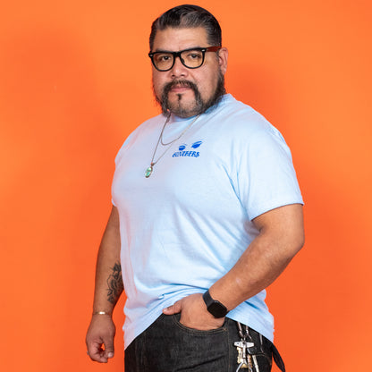 Man wearing a light blue t-shirt with a logo against an orange background