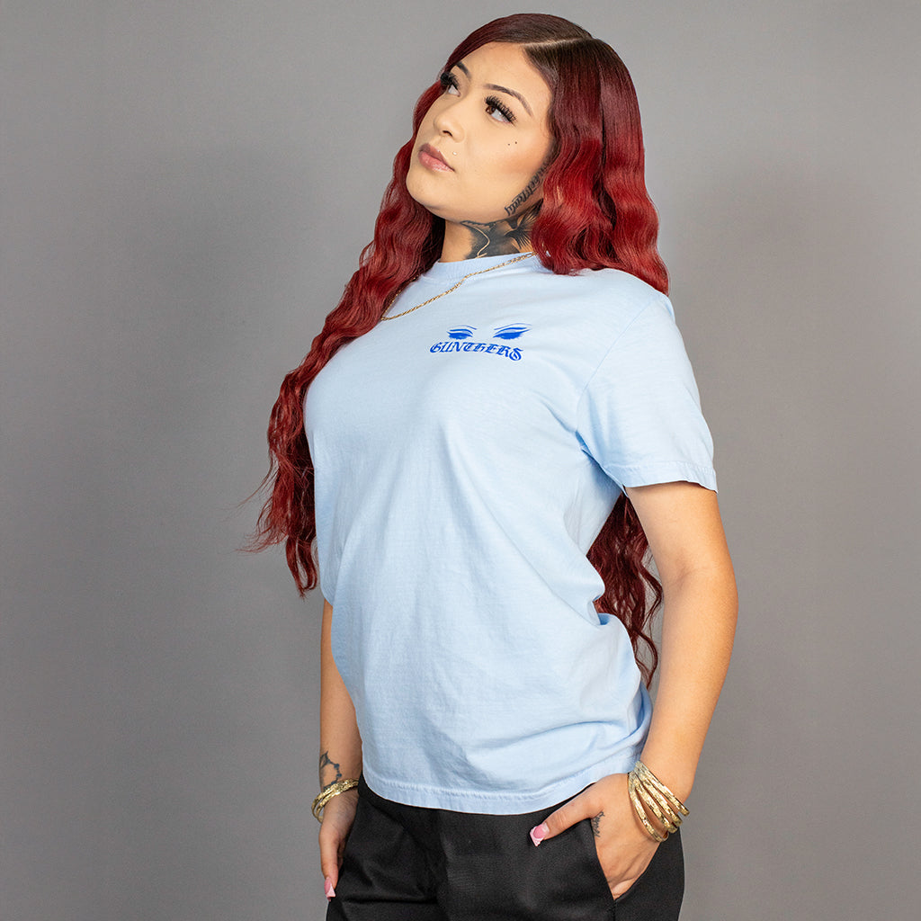Woman wearing a light blue t-shirt with a logo on a gray background