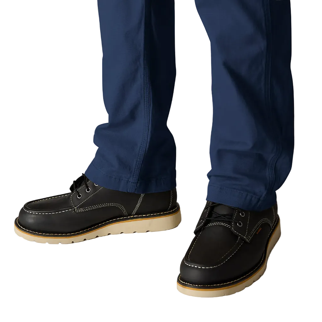 Black leather shoes with brown soles worn with blue pants on a light gray background