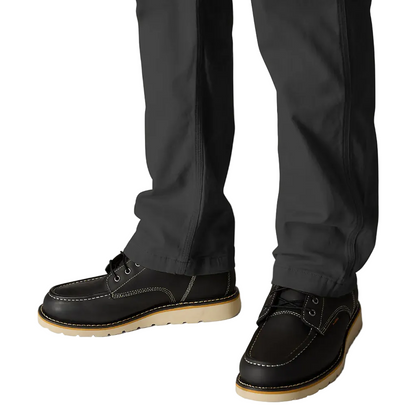 Black leather shoes with brown soles worn with dark pants on a white background