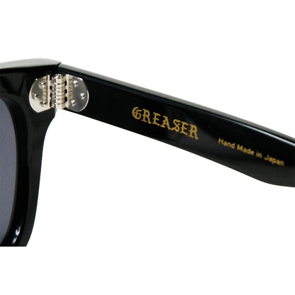 Black sunglasses with 'GREASER' branding on a white background