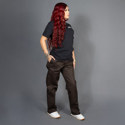 Person wearing a black shirt and brown pants against a gray background