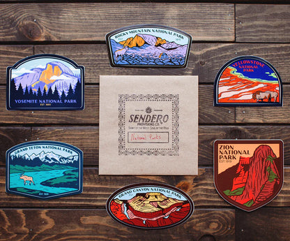 National park stickers on a wooden surface with a Sendero paper product.