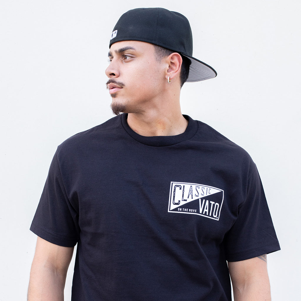 Man wearing a black t-shirt with a logo and a black cap on a light gray background