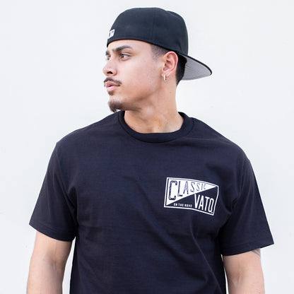 Man wearing a black t-shirt with a logo and a black cap on a light gray background