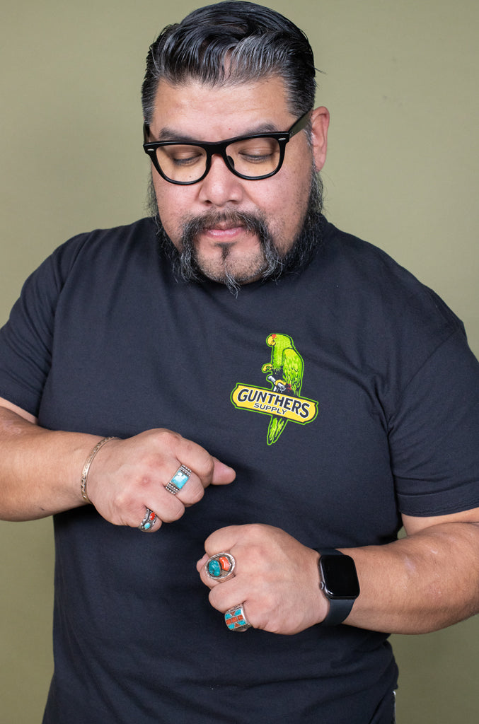 Man wearing a black t-shirt with a logo, posing against a plain background