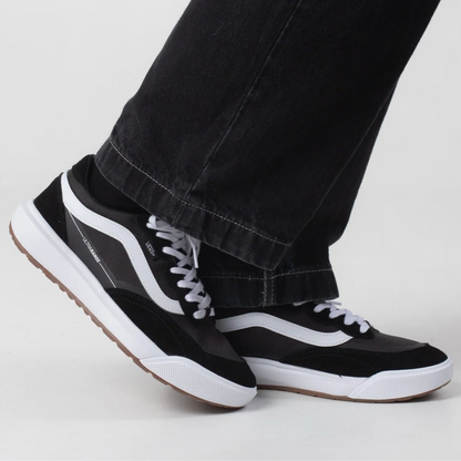 Black and white sneakers worn with black pants on a light gray background