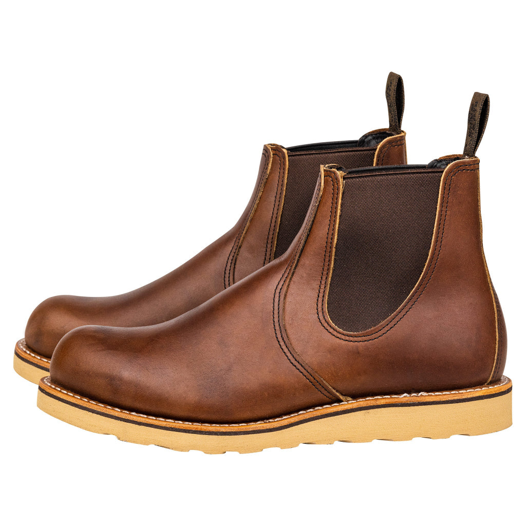 A pair of brown leather Chelsea boots with a pull-on silhouette and a yellow outsole.